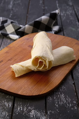 Rolled pita on wooden board with a napkin on a table.