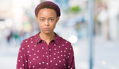 Beautiful young african american woman wearing head scarf over isolated background skeptic and nervous, frowning upset because of problem. Negative person.