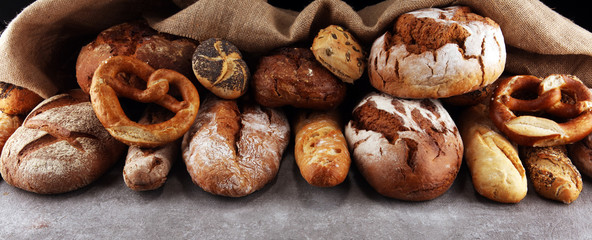 Assortment of baked bread and bread rolls on stone table background