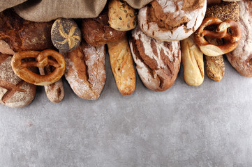 Assortment of baked bread and bread rolls on stone table background