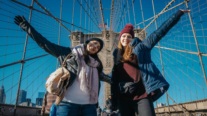 Two girls walk over the famous Brooklyn Bridge in New York