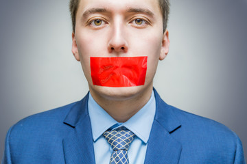 Censorship concept. Man is silenced with red adhesive tape on his mouth