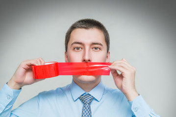 man with wrapping adhesive tape around mouth. Businessman silenced with duct tape over his mouth....