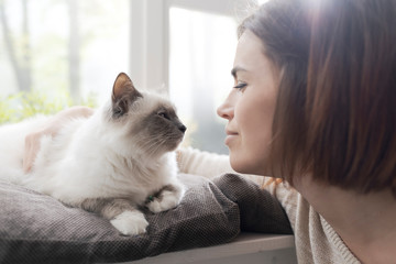 Woman petting her cat next to a window
