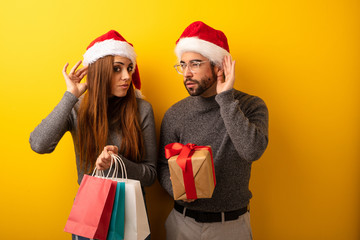 Couple or friends holding gifts and shopping bags try to listening a gossip