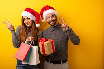 Couple or friends holding gifts and shopping bags doing a gesture of victory