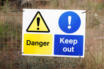 Danger keep out safety sign on fence at construction building site