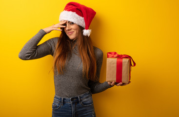 Young pretty woman holding gift embarrassed and laughing at the same time