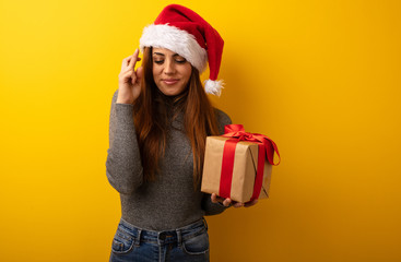 Young pretty woman holding gift crossing fingers for having luck