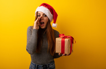 Young pretty woman holding gift shouting something happy to the front