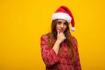 Young woman wearing santa hat thinking about an idea