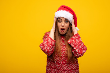Young woman wearing santa hat surprised and shocked