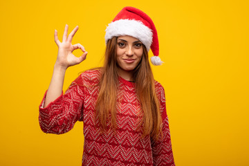 Young woman wearing santa hat cheerful and confident doing ok gesture