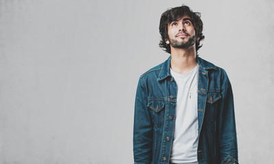 Young handsome man looking up, thinking of something fun and having an idea, concept of imagination, happy and excited