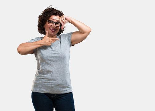 Middle aged woman making a frame shape with hands, trying to focus as if it were a camera