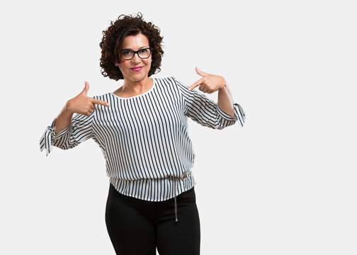 Middle aged woman proud and confident, pointing fingers, example to follow, concept of satisfaction, arrogance and health