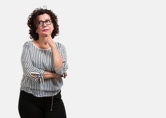 Middle aged woman thinking and looking up, confused about an idea, would be trying to find a...