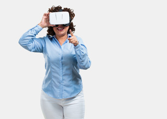Middle aged woman excited and entertained, playing with virtual reality glasses, exploring a fantasy world, trying to touch something