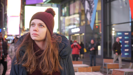 Beautiful girl walks through the city of New York at Times Square by night