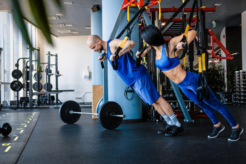 Obraz premium Couple workout in the gym, doing exercise with functional loops.
