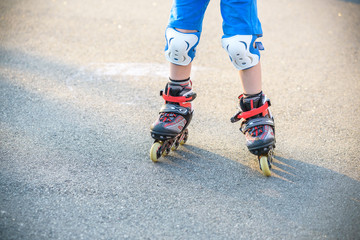 Little boy learning to roller skate in summer park. Children wearing protection pads for safe...