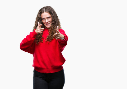 Beautiful brunette curly hair young girl wearing glasses and winter sweater over isolated background pointing fingers to camera with happy and funny face. Good energy and vibes.