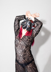 Beautiful woman with red long hair wearing a lacy dress and mask. Beauty portrait of modern fashion, white background.