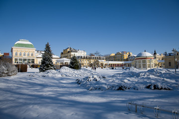 Sunny day in the center of small spa town Frantiskovy Lazne (Franzensbad) in winter under snow -...