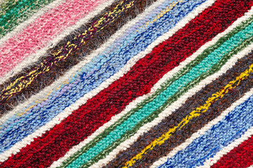 different colored stripes on the knitted fabric surface. background close-up of textiles retro rugs or rugs. the texture of the fabric is a combination with the geometry of the lines. handmade product