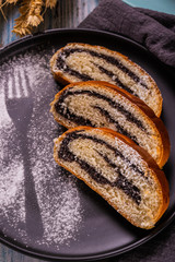 Poppy seed strudel on dark plate with silhouette of fork made by sugar