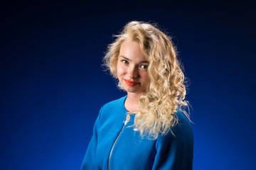 Beautiful woman with blonde long curly hair. Beauty portrait of modern fashion, blue background.