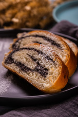 Poppy seed strudel on dark plate with powder sugar