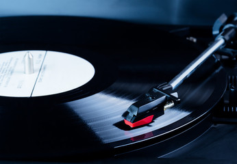 Vinyl record player needle above a rotating disc.