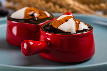 White whipped cream in two nice small red cups with handle