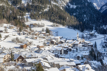 Village in a narrow valley in winter afternoon in the swiss alps.