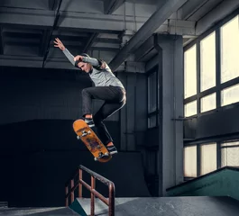 Rolgordijnen Skateboarder performing a trick on mini ramp at skate park indoor. © Fxquadro