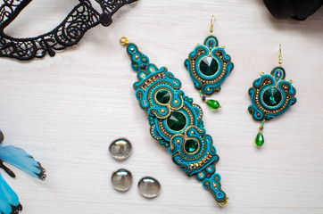 Beaded bracelet and earrings set. Turquoise soutache jewelry on the white wooden background. Women accessories