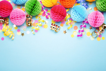 Birthday party background on blue. Top view. Border made of colorful serpentine, balls and confetti.