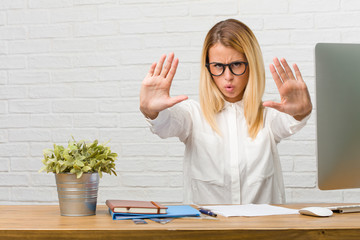 Portrait of young student sitting on her desk doing tasks serious and determined, putting hand in...
