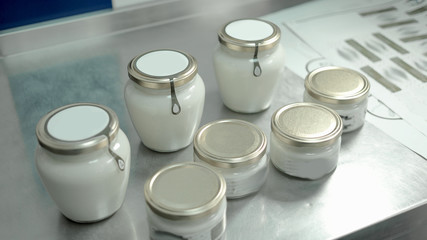 Jars with natural sour cream at dairy factory. Eco farm dairy product. Benefits of glass packaging.