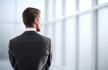 rear view.businessman standing near the office window