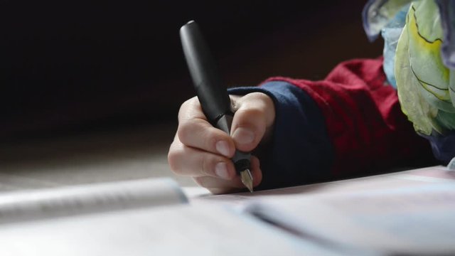Boy writing with a pen on paper, closeup footage, homework