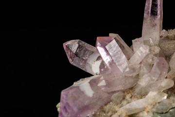Macro mineral stone Amethyst crystals in rock on a black background