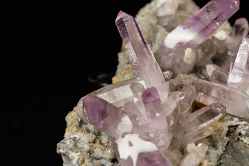 Macro mineral stone Amethyst crystals in rock on a black background