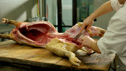Butcher cuts pork carcass in a slaughterhouse. Processing of pig carcasses in a slaughterhouse....