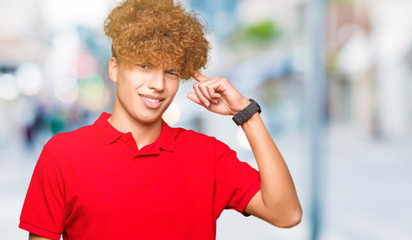 Young handsome man with afro hair wearing red t-shirt Smiling pointing to head with one finger, great idea or thought, good memory