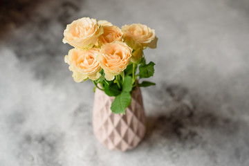 Beautiful fresh beige roses in a clay vase on a concrete background. Laying and decoration of a table