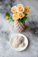 Beautiful fresh flowers in a vase and sweet on a plate on a table. It can be used as a background