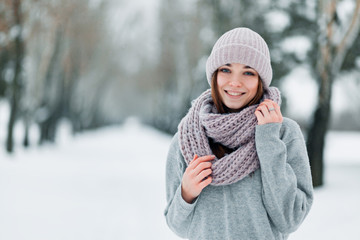 beautiful smiling girl stands on the road in a hat and sweater in winter