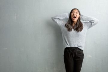 Fototapeta premium Young indian woman against a grunge wall surprised and shocked, looking with wide eyes, excited by an offer or by a new job, win concept